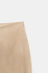 Falda corta de tiro bajo con tejido efecto ante, bajo asimétrico y aplicación de flecos largos a tono. Cuenta con cierre lateral con cremallera oculta.