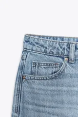 Jeans celeste de tiro alto, corte recto y largo, con cinco bolsillos y cierre frontal con cremallera y botón.