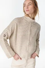 Campera de punto a rayas horizontales en tonos beige y crudo, con cuello alto, cierre frontal y manga larga con detalle de bordado en la manga.
