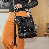 Cartera tipo hobo de cuero vacuno negro con apliques metálicos y detalles de cuero con textura de cocodrilo. Tiene correa de hombro ajustable y manija corta.