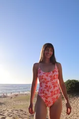 Malla enteriza de traje de baño con estampado floral en tonos coral y rosa claro. Presenta escote redondo en el frente y espalda baja, con tirantes finos.