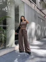 Conjunto de dos piezas compuesto por un top sin mangas de cuello redondo y un pantalón de corte ancho con cintura elástica y cordón ajustable. Ambas prendas están confeccionadas en tela morley con textura de líneas finas en color marrón chocolate.
