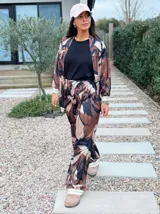 Conjunto de kimono y pantalón de seda con estampado abstracto en tonos marrones y negros. El kimono es de corte holgado con mangas largas y el pantalón es de corte fluido con cintura ajustable.