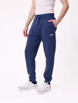 Babucha jogger color gris oscuro, con cintura elástica ajustable con cordón, bolsillos laterales y puños elásticos en los tobillos. Presenta un logo estampado en el muslo izquierdo.