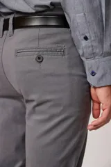 Pantalón de vestir color beige, confeccionado en algodón con spandex. Corte recto, con bolsillos laterales y traseros. Se ajusta a la cintura con cinturón de cuero trenzado en tonos azul y beige.