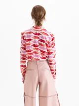 Camisa de seda con estampado de labios en tonos rojos y rosas. Presenta cuello clásico, cierre frontal con botones ocultos y mangas largas con puños abotonados.