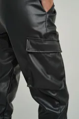 Pantalón babucha negro de cuero sintético con cintura elastizada con cordón ajustable, bolsillos laterales y bolsillos tipo cargo con solapa en los laterales de las piernas.