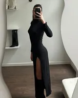 Vestido largo negro de cuello alto y manga larga, con un tajo lateral profundo que llega hasta el muslo.