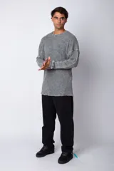 Buzo de corte oversize confeccionado en tela waffle de algodón con proceso de teñido acid wash. Presenta cuello redondo con detalle de costura en X y mangas largas con puños acanalados.