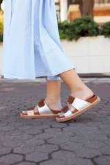 Sandalias bajas con base color suela, tiras anchas horizontales de cuero color marrón y plateado.