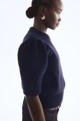 Top de punto acanalado en color azul marino, con cuello redondo, mangas cortas abullonadas y terminaciones acanaladas en puños y ruedo.