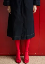 Abrigo largo de denim color azul oscuro, con cuello de solapa, cierre frontal de botones y cinturón ajustable tipo batín. Presenta diseño recto, manga larga y dos bolsillos laterales.