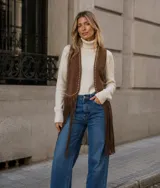Chaleco de estilo boho confeccionado en cuero sintético color marrón, con flecos largos en el ruedo y detalle de tachas metálicas a lo largo de los bordes frontales.