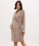 Bata de baño de plush color marrón, con mangas largas, cuello amplio, bolsillo delantero y lazo ajustable en la cintura. Presenta detalles de ribete estampado en los bordes y puños.
