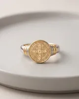 Anillo de plata y oro con diseño de San Benito, presenta una medalla circular grabada en el frente y detalles de alambre en los laterales del aro.