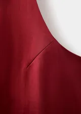 Vestido corto de tejido satinado en color bordó, sin mangas, con cuello redondo y diseño recto.