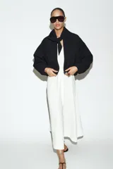 Chaqueta bomber negra con cuello redondo y pañuelo desmontable anudado al frente. Presenta cierre frontal con cremallera, bolsillos laterales con solapa y botones a presión, y terminaciones elásticas abullonadas en puños y ruedo.
