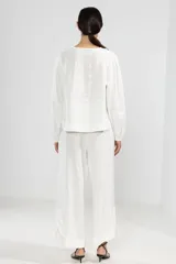 Pantalón blanco de lino italiano, de pierna ancha, con cintura elástica ajustable con cordón, bolsillos laterales y cortes redondeados en los laterales.