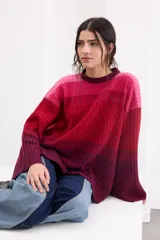 Sweater de punto con diseño en degradé de tonos fucsia, rosado y bordó. Presenta cuello a la base, corte recto holgado y mangas largas amplias con tajos en los puños.