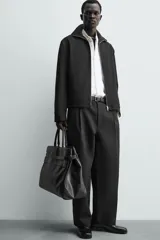 Sobrecamisa relaxed fit de Zara confeccionada en tejido negro con estructura diagonal. Presenta cuello subido, manga larga, bolsillos de vivo en la cadera y cierre frontal con cremallera.