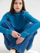 Polera básica de algodón en tejido rib, color turquesa, de manga larga, con hombreras y detalles de pespuntes en color contrastante en las terminaciones y el cuello.