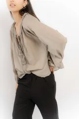 Blusa celeste de algodón con escote en V con lazos y mangas largas abullonadas con puños elásticos.