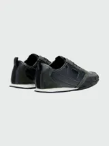 Zapatillas deportivas Diesel modelo S-Pagodha, con diseño de paneles en cuero y gamuza en tonos verde oscuro y negro. Presentan suela de goma robusta con relieve geométrico que se extiende hacia la puntera, cordones negros y detalle de logo en la lengüeta.