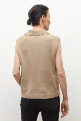 Chaleco de punto color tostado melange, con cuello polo y abotonadura frontal de tres botones. Sin mangas.