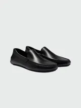 Mocasines de cuero negro con diseño clásico, costuras visibles en la puntera y detalle de logo grabado en el lateral.
