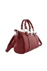 Cartera de mano color bordó con doble asa corta, correa larga ajustable y extraíble, y detalle de tachas metálicas verticales en el frente. Incluye un aplique metálico decorativo en forma de labios con strass en la parte superior central.