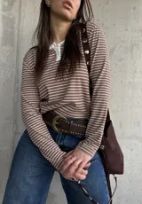 Remera de manga larga a rayas horizontales en tono tostado y blanco, con cuello redondo y cartera de botones frontal.