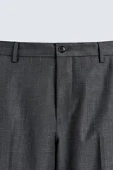 Pantalón de traje regular fit color gris oscuro, confeccionado en tejido con lana, con bolsillos frontales y bolsillos traseros de doble vivo con botón. Cierre frontal con cremallera y botón.