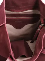 Cartera tipo tote bag de gamuza color bordó, con doble asa larga para el hombro y costura vertical central con detalle de etiqueta grabada.