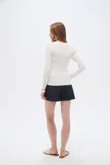 Remera de manga larga al cuerpo confeccionada en viscosa, de color blanco, con cuello a la base y cierre frontal de botones.