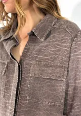 Chaqueta color crudo con cuello camisero, cierre frontal con botones, mangas 3/4 con puños arremangados y dos bolsillos de parche en el pecho.