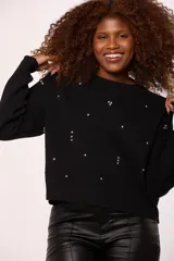 Buzo tejido de punto color negro, con cuello redondo, mangas largas y detalle de pequeñas piedras brillantes (strass) distribuidas por toda la prenda.