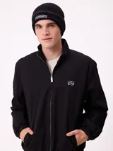 Gorro tipo beanie de tejido acanalado en color negro, con etiqueta frontal bordada con el logo de la marca Rusty.