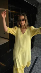 Vestido largo color amarillo pálido, con escote en V, mangas cortas abullonadas con detalle de calado y ruedo con volantes y calado.