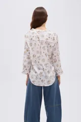 Blusa de viscosa color beige con cuello en V, cierre parcial de botones frontales, bolsillo en el pecho y mangas 3/4.