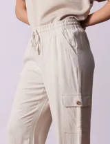 Pantalón cargo de lino a rayas verticales grises y blancas, marca Marissa Olivia. Pretina ancha elastizada con lazo de ajuste, bolsillos inclinados delanteros y bolsillos laterales con botón.