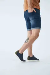 Bermuda de jean azul con lavado clásico, diseño de cinco bolsillos, cierre de cremallera y botón, con detalle de botamanga doblada.