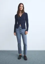 Pantalón de jean estilo flare con tiro medio, diseño crop y bajo deshilachado. Cuenta con cinco bolsillos, cierre de cremallera y botón, y trabillas para cinturón.