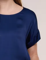 Blusa azul marino de silueta relajada confeccionada en satén, con escote redondo, hombros caídos y mangas cortas de corte japonés con puño doblado.