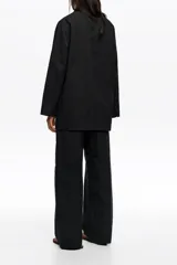 Chaquetón sastrero negro de doble botonadura en mezcla de algodón y poliamida, con solapas de muesca, mangas largas, bolsillos frontales de parche y pespuntes decorativos.