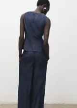 Top sin mangas de efecto denim con cuello redondo y diseño ajustado en la cintura con ligero vuelo en el bajo. Cuenta con cierre de botón en la parte posterior del cuello.