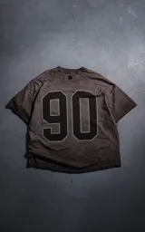 Remera manga corta de calce oversize en color chocolate con efecto batik. Presenta un estampado numérico '90' en la espalda y cuello redondo.