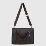 Tote bag de diseño rectangular con estampado animal print en tonos oscuros. Cuenta con doble asa de mano, correa ajustable y extraíble con logo de la marca, cierre superior y un dije colgante con la letra B en color violeta.