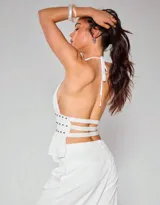 Top blanco con escote halter y espalda descubierta, confeccionado en microtul con detalle de tachas en la cintura.