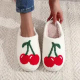 Pantuflas blancas con interior de felpa y estampado de cerezas rojas con hojas verdes.