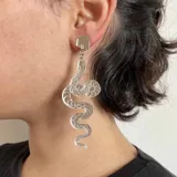 Par de aros colgantes con forma de serpiente plateada con detalles en negro.